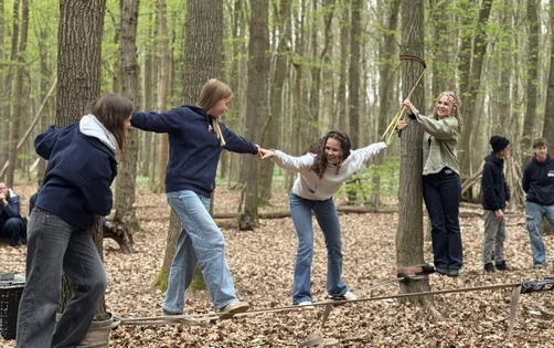 Jugendliche auf einer Slackline im Wald.