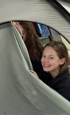 Jugendliche schaut aus einem Zelt