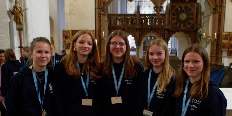 Mehrere junge Frauen schauen in die Kamera und haben Teamercards am Band um den Hals hängen