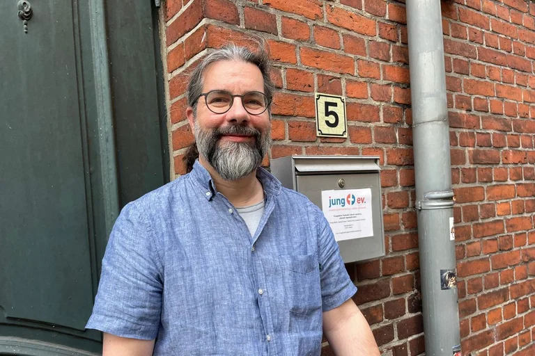 Mann schaut lächelnd in die Kamera