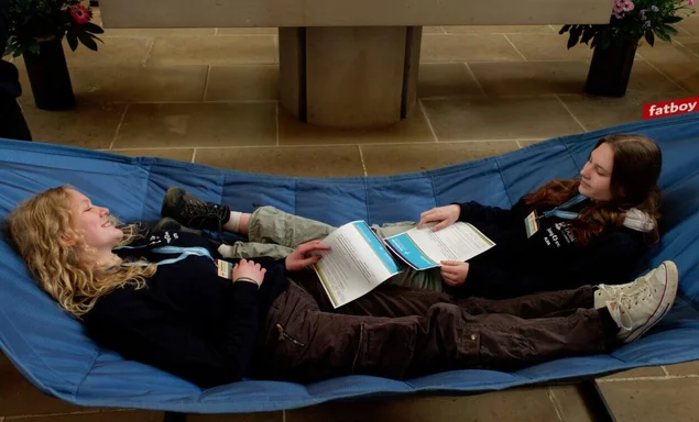 Zwei junge Frauen liegen in einer Hängematte.